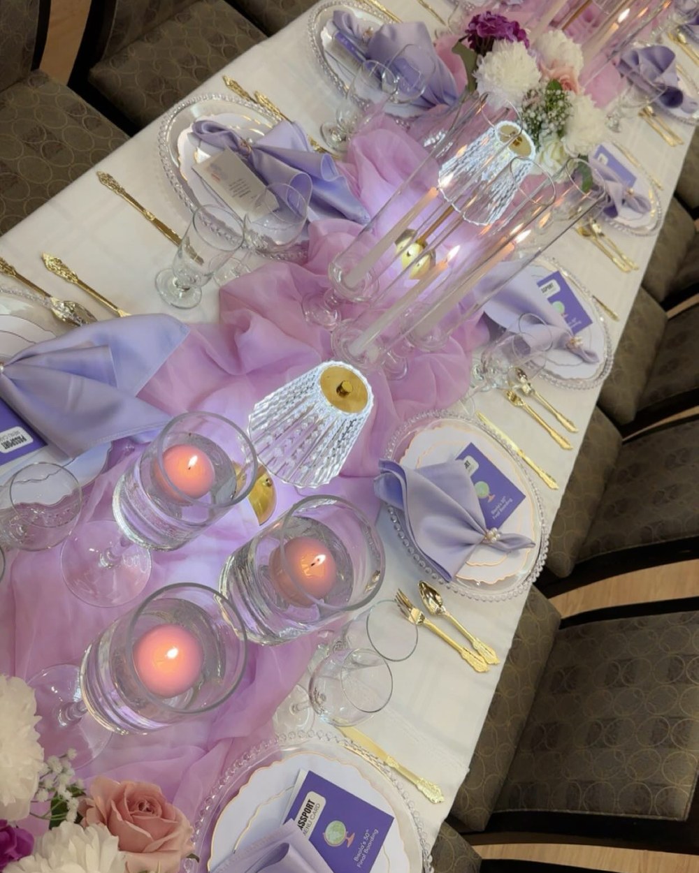Close detail of a place setting with lilac linen, gold cutlery and candlelight