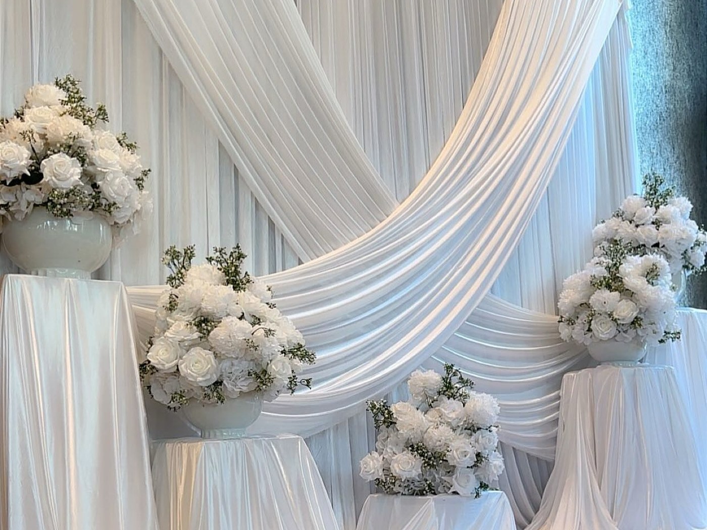 White draped backdrop banked with ivory florals behind a head table