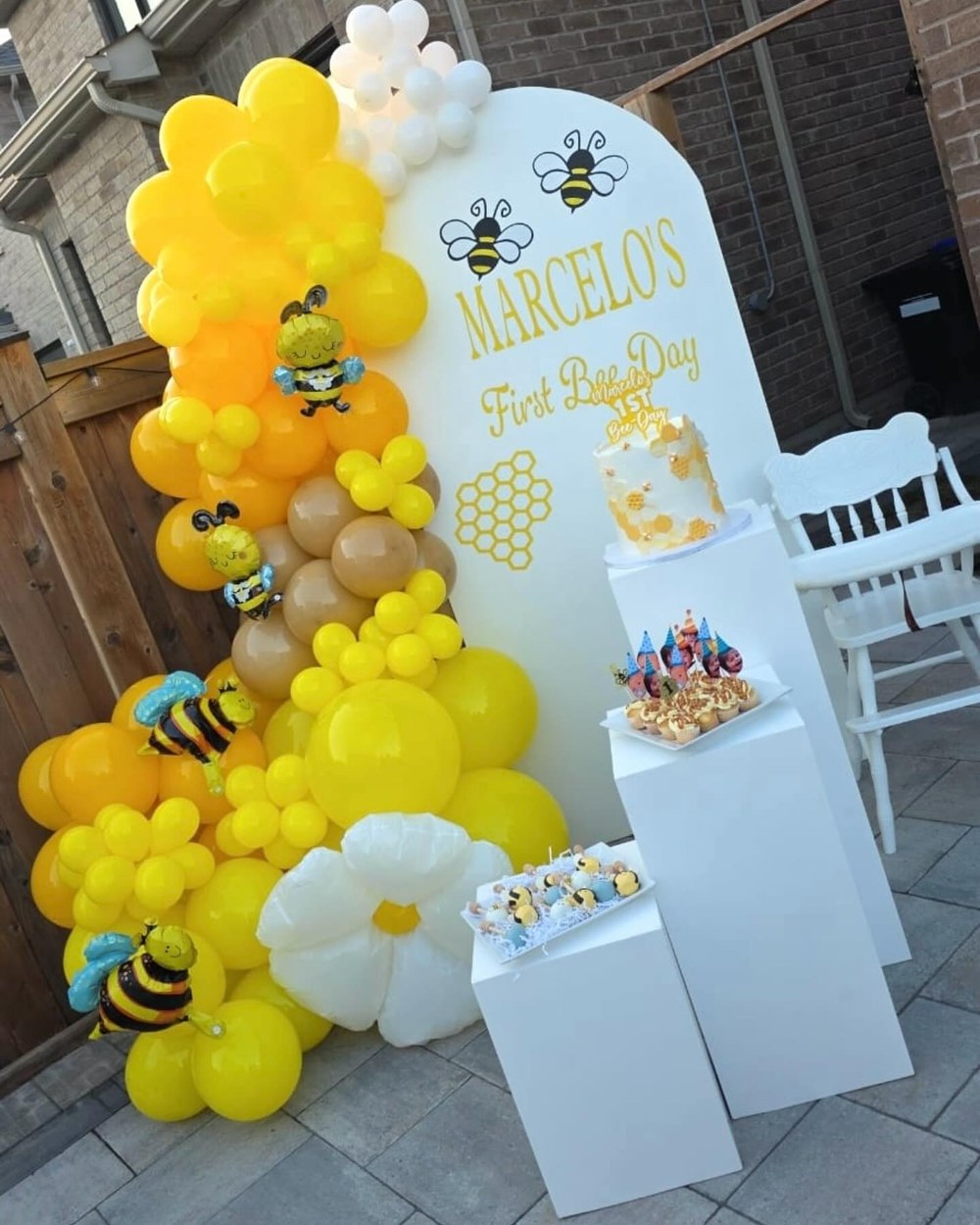 First birthday setup with a yellow and white balloon garland and bee details