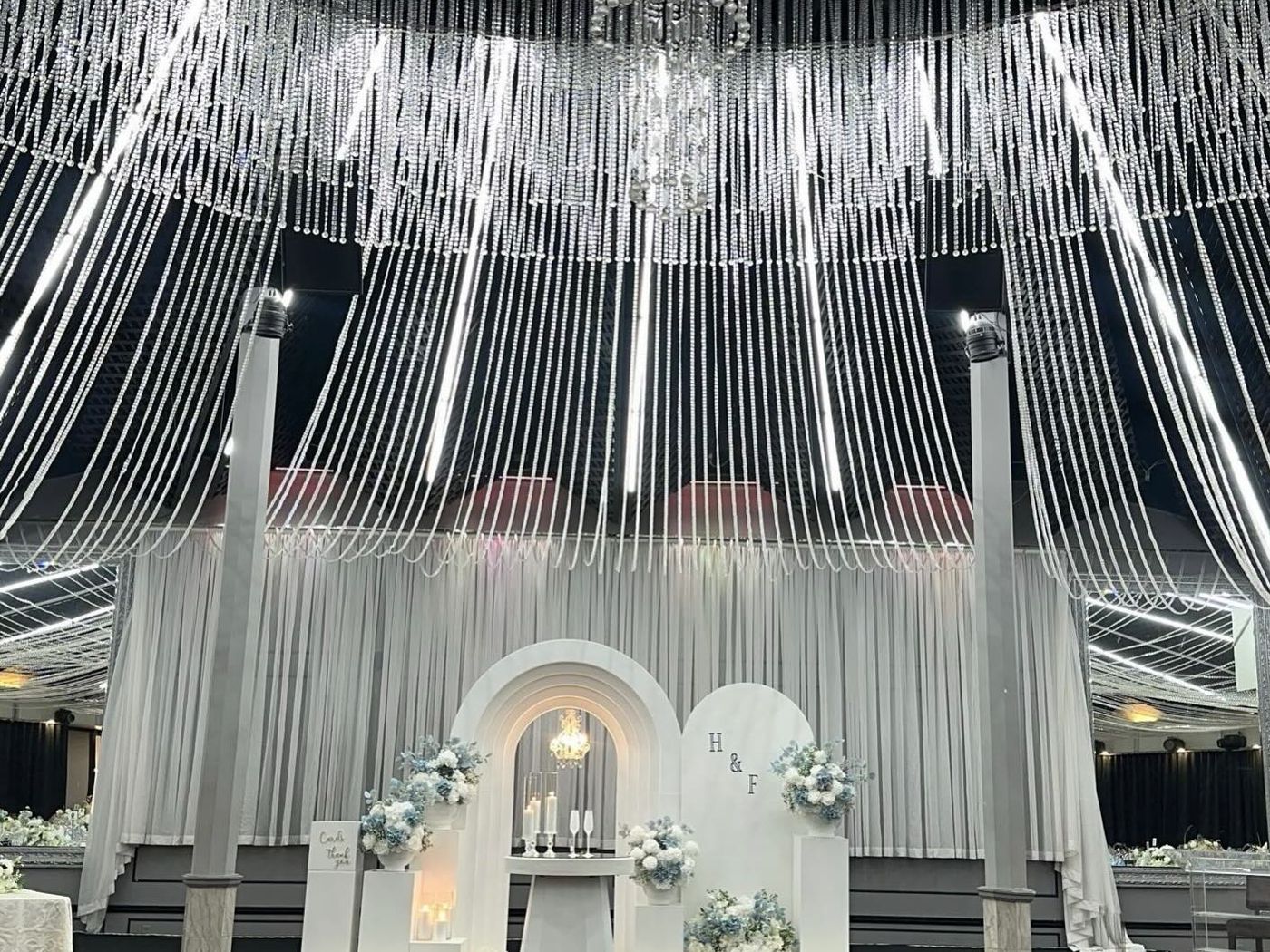 Ballroom with a cascading fringe ceiling installation above a white arch stage